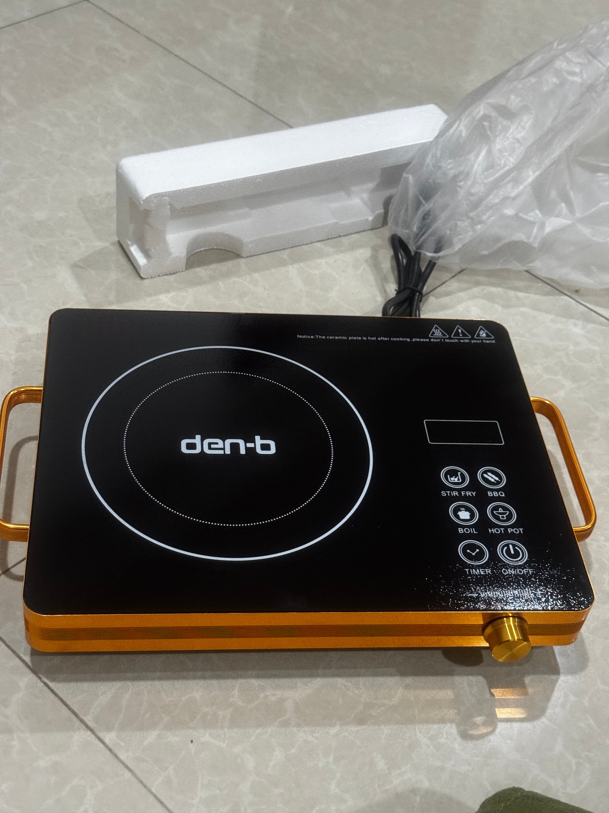 Induction cooktop with brand logo on a tiled floor